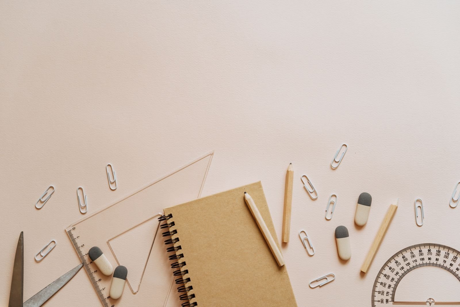 A kraft notebook and stationery arranged on a warm neutral desk